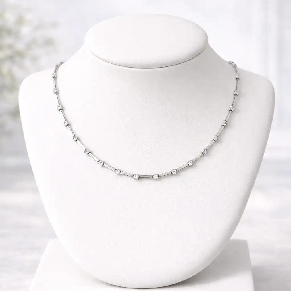 Silver necklace on a white mannequin bust against a white background