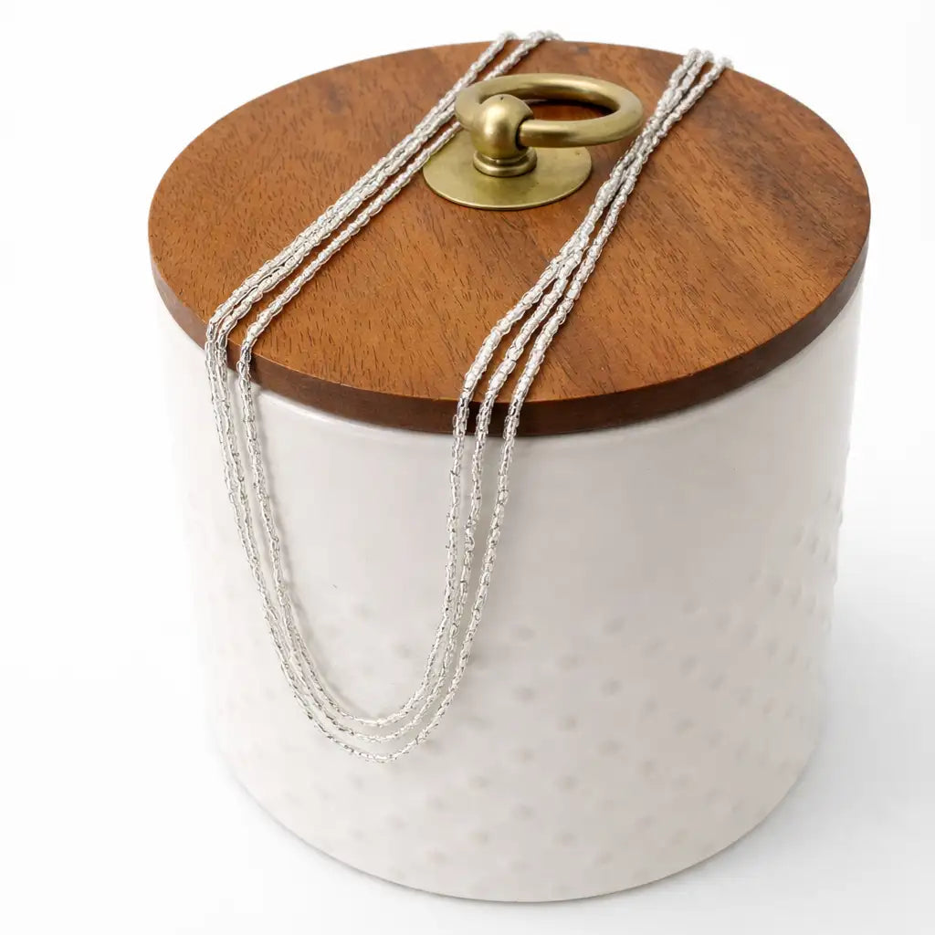 Silver Jewelry triple layer necklace placed in a decorative container with wooden lid