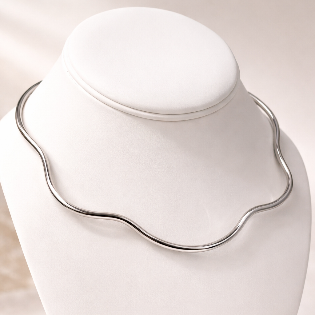 Silver necklace on a white mannequin bust against a beige background