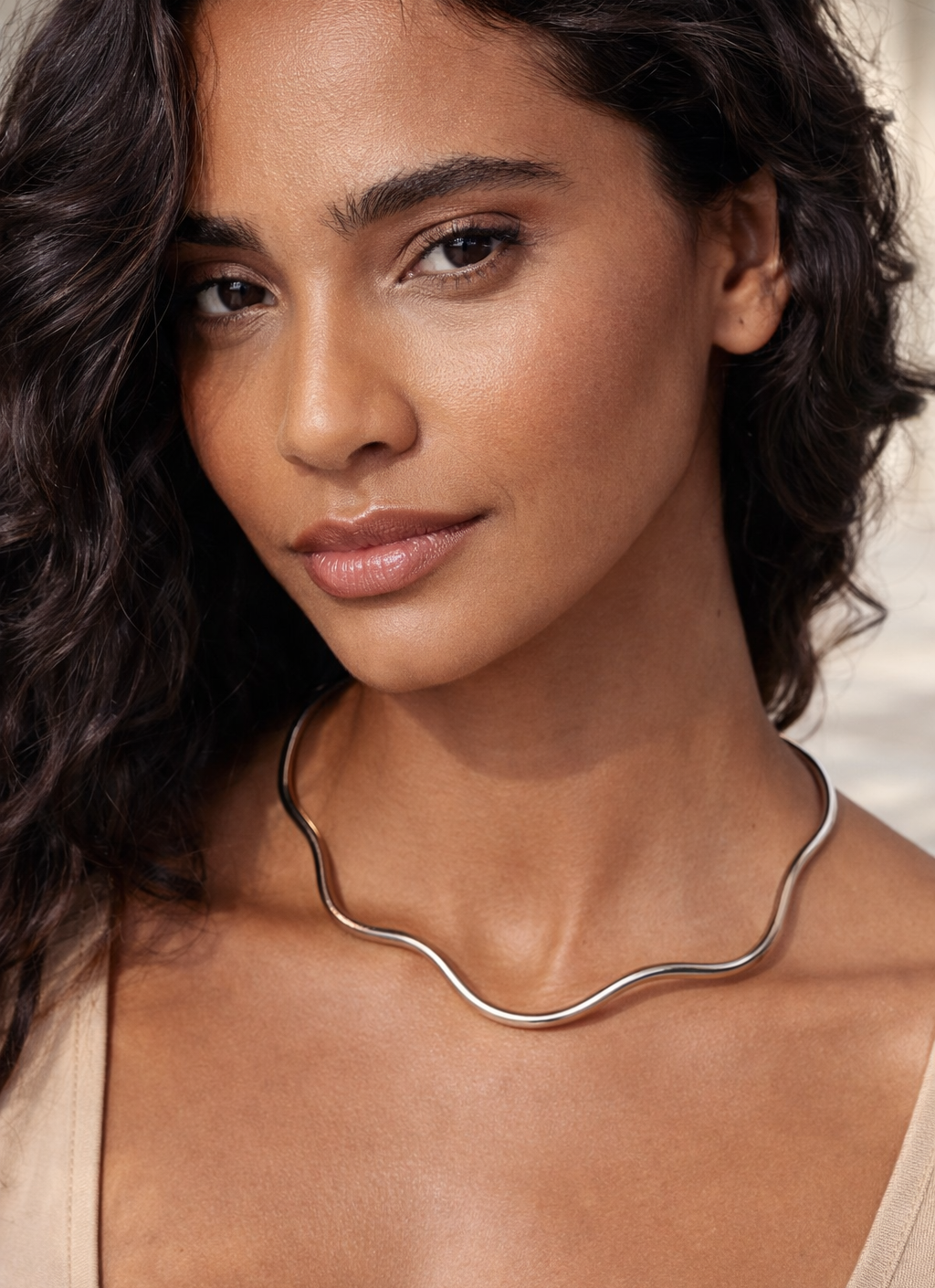 Woman wearing a silver necklace with a neutral background
