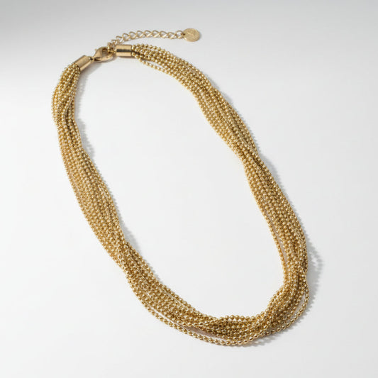 Gold beaded necklace on a light gray background